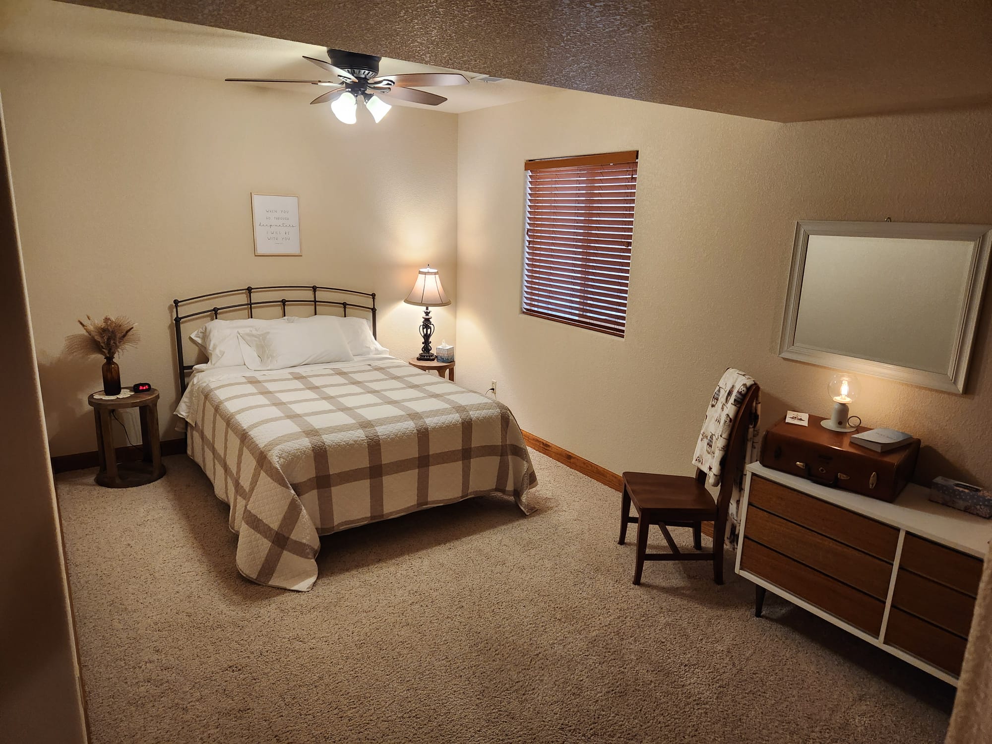 A cozy bedroom at Denver Guest Home with a queen-sized bed, plaid bedding, side table, and warm lighting.