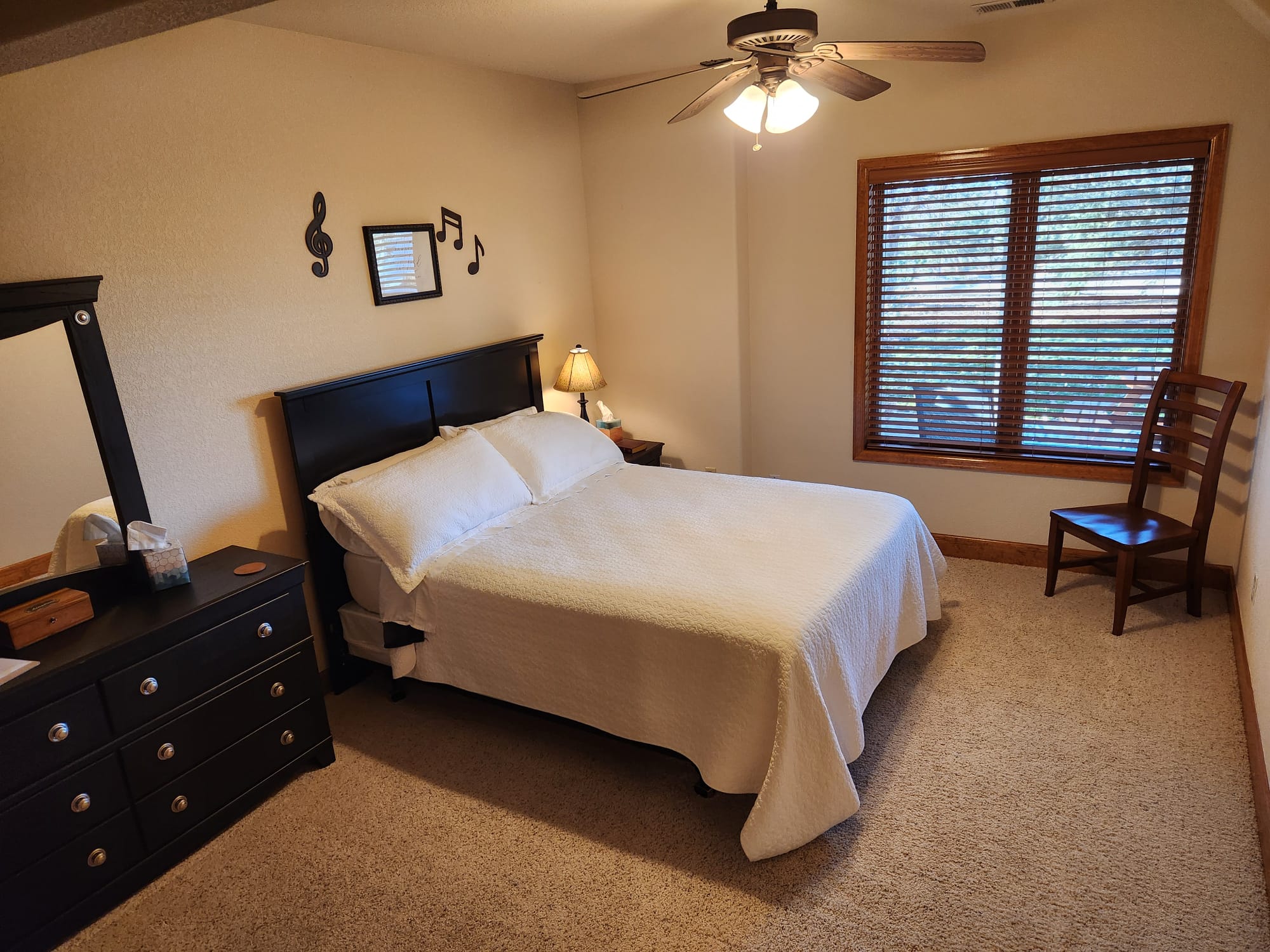 A cozy bedroom at Denver Guest Home with a black bed frame, white bedding, musical wall decor, and natural light.