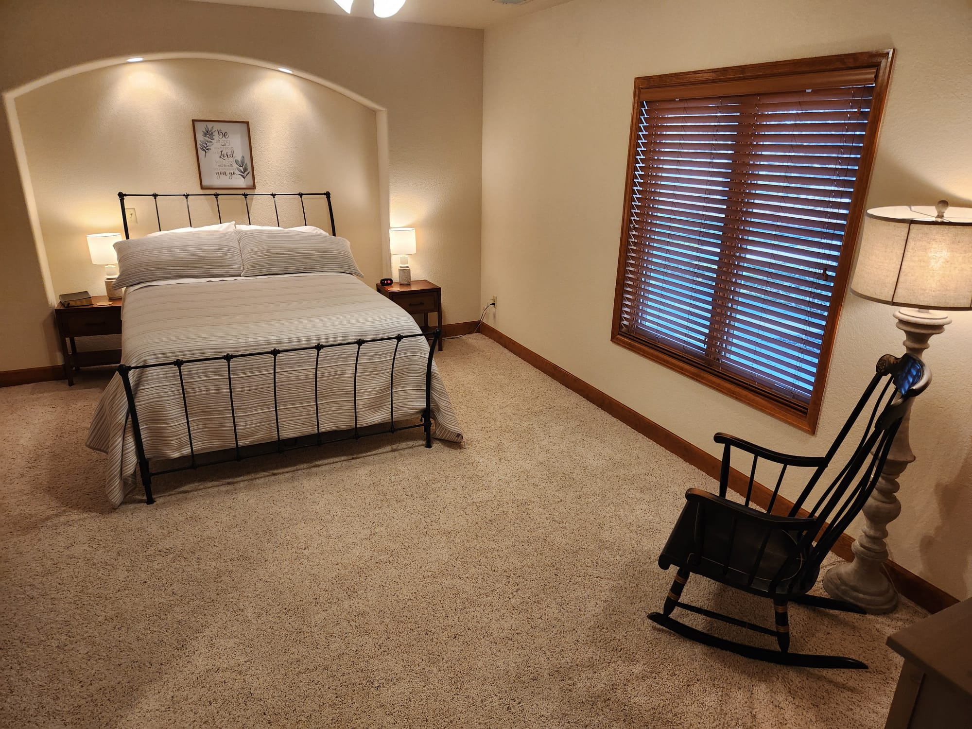 A spacious bedroom at Denver Guest Home with a wrought iron bed, striped bedding, and a rocking chair.